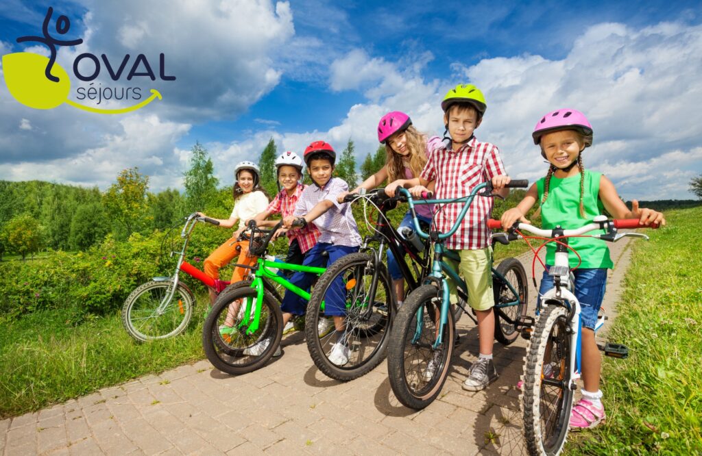 Children in row wearing helmets holding bikes