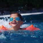 Petit garçon qui nage dans une piscine avec des brassards